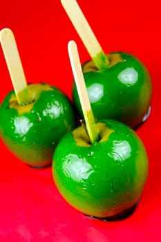 Green toffee apples isolated against a red background