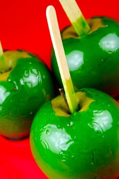 Green toffee apples isolated against a red background