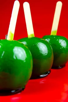 Green toffee apples isolated against a red background