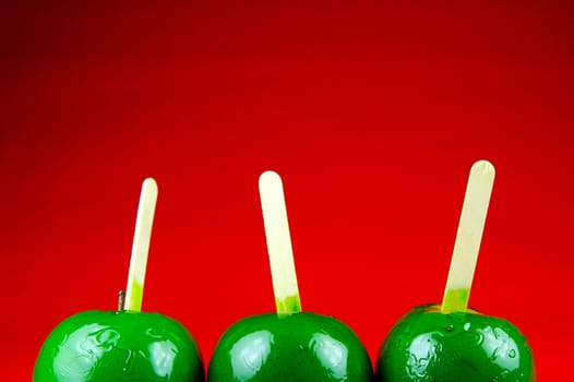 Green toffee apples isolated against a red background