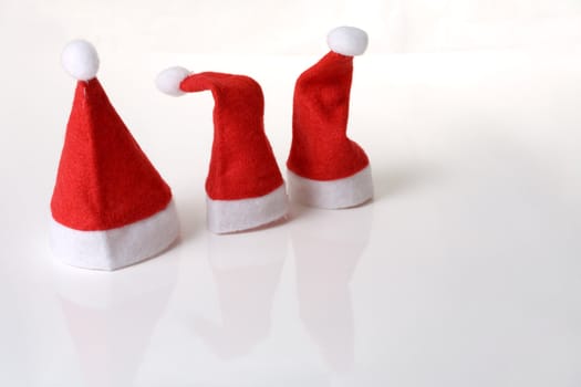 Three small christmas hats in a row on white