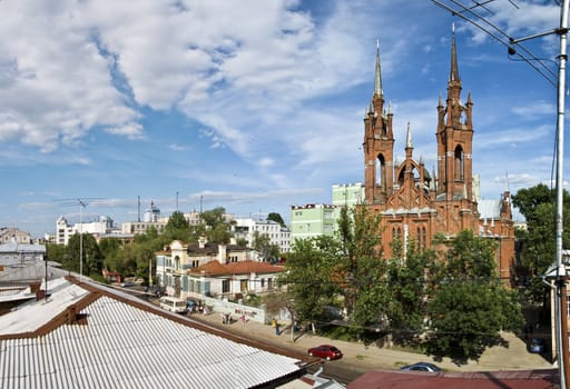 Panorama of large size. Urban Catholic cathedral in the heart of the city of Samara. Russia. Against the background of blue sky with clouds. Taken from the roof of a house.