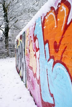 A graffiti wall in a park, covered with snow.             