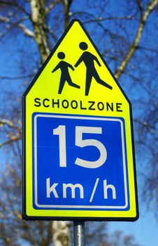 Schoolzone traffic sign against a blue sky.