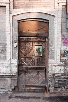 The old wooden door in a brick house. The rusty mailbox. The door is closed the lock.