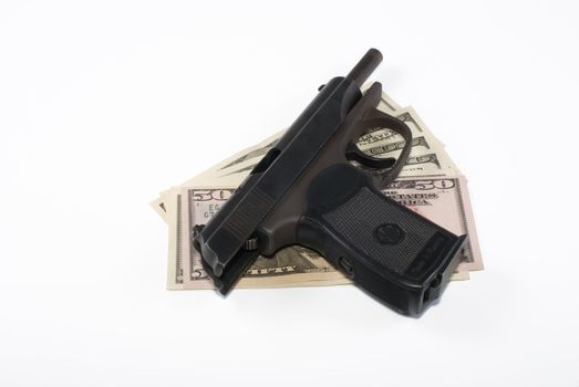 The pistol lays on dollar banknotes on a white background