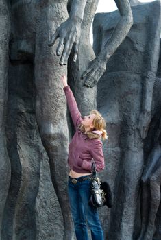 The young smiling girl stretches a hand to a monument