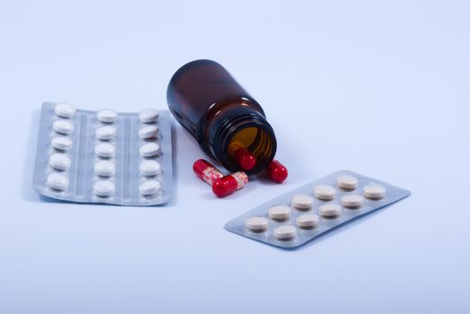 Packings with tablets and a vial with capsules on a white background