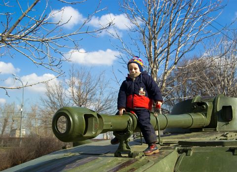 The smiling boy sits on a tank gun