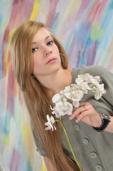 Portrait of long-haired beautiful girl 16-17 years with orchid