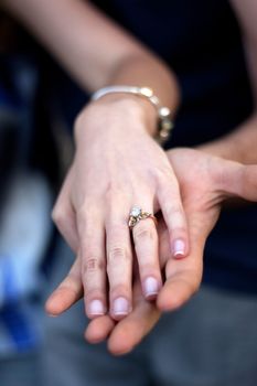 Close up of a young couples hands and diamond engagement ring with platinum and gold accents. Shallow depth of field.