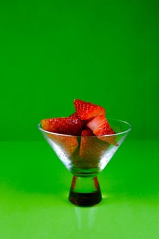 Strawberries in a cocktail glass islolated against a green background