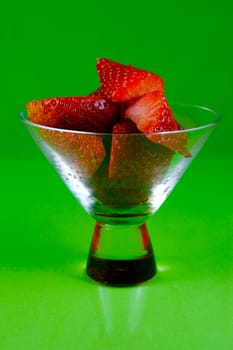 Strawberries in a cocktail glass islolated against a green background