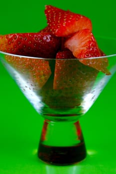 Strawberries in a cocktail glass islolated against a green background