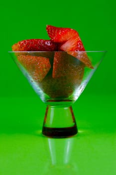 Strawberries in a cocktail glass islolated against a green background