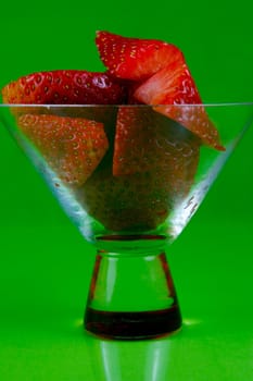 Strawberries in a cocktail glass islolated against a green background