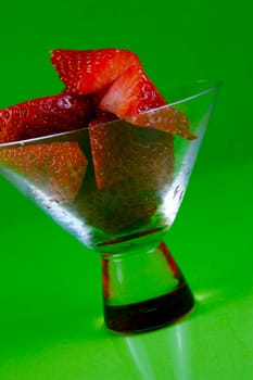 Strawberries in a cocktail glass islolated against a green background