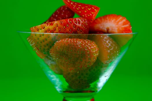 Strawberries in a cocktail glass islolated against a green background