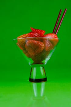 Strawberries in a cocktail glass islolated against a green background