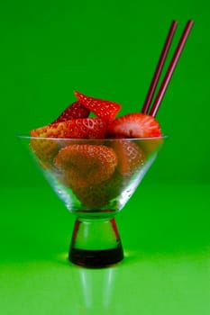 Strawberries in a cocktail glass islolated against a green background