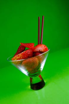 Strawberries in a cocktail glass islolated against a green background