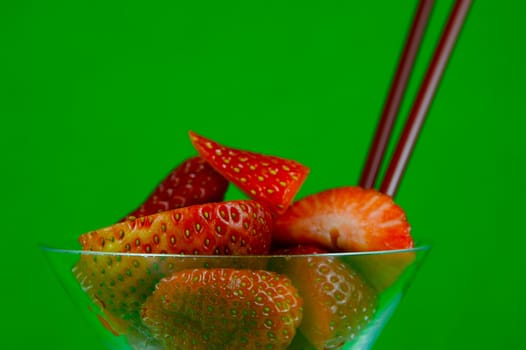 Strawberries in a cocktail glass islolated against a green background