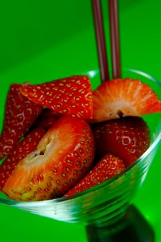 Strawberries in a cocktail glass islolated against a green background