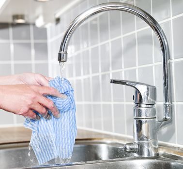 Hand holding a Dish Cloth under running water