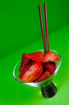 Strawberries in a cocktail glass islolated against a green background