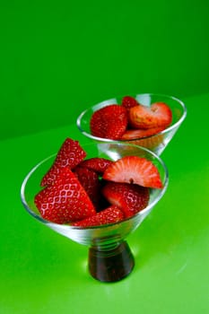 Strawberries in a cocktail glass islolated against a green background