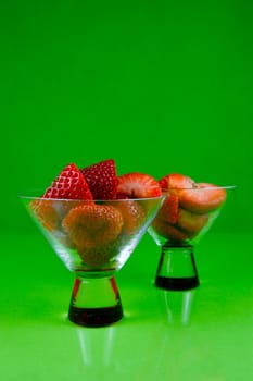 Strawberries in a cocktail glass islolated against a green background