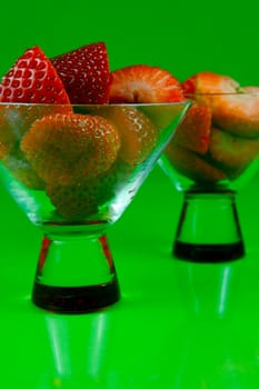 Strawberries in a cocktail glass islolated against a green background