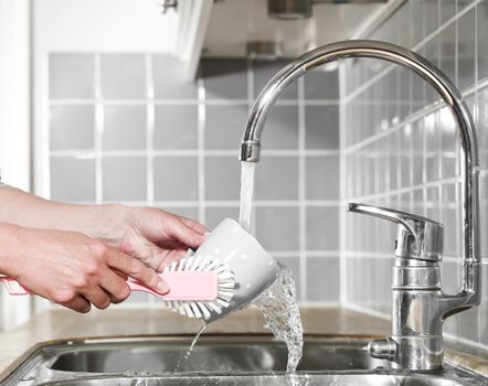 Close up of a human washing a coffee cup