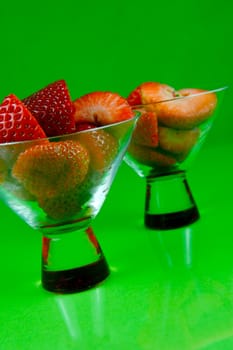 Strawberries in a cocktail glass islolated against a green background