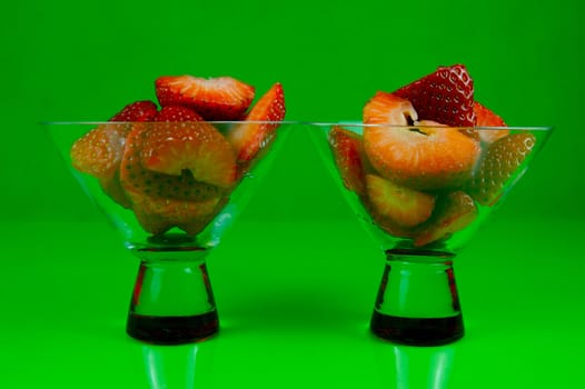 Strawberries in a cocktail glass islolated against a green background