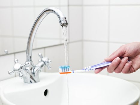 Human holding a Toothbrush with toothpaste in the bathroom
