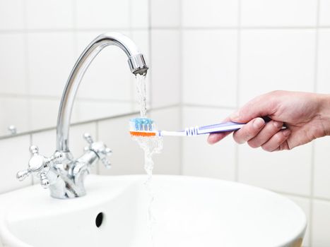 Human holding toothbrush in water