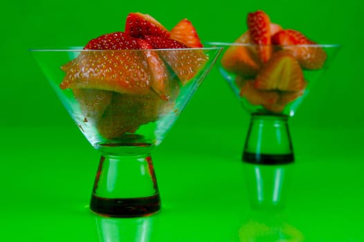 Strawberries in a cocktail glass islolated against a green background