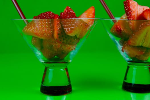 Strawberries in a cocktail glass islolated against a green background