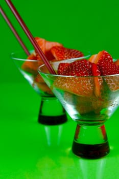 Strawberries in a cocktail glass islolated against a green background