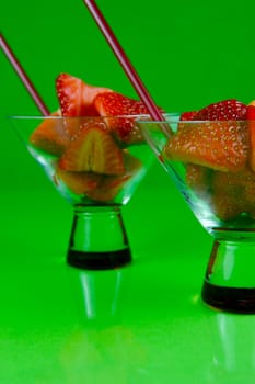 Strawberries in a cocktail glass islolated against a green background