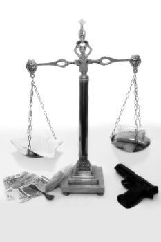 an antique scales against a white background with drugs and gun depicting drug crime