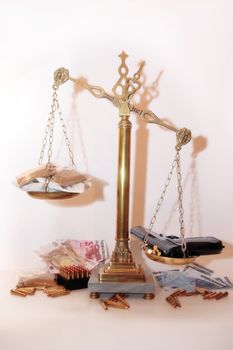 an antique scales against a white background with drugs and gun depicting drug crime