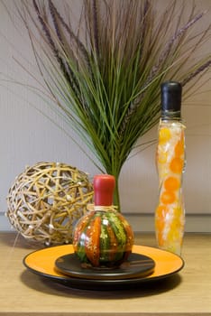 Decorative bottles, straw sphere, leaf and the ceramic plate on the table