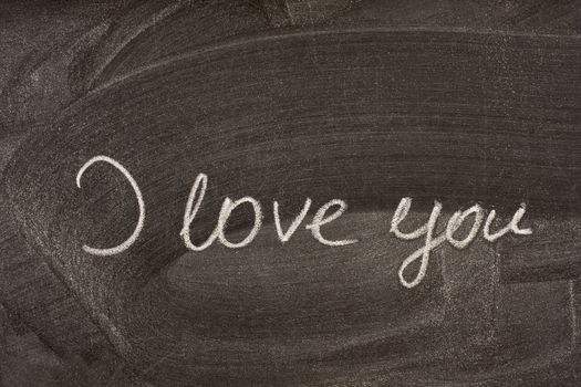I love you handwritten with white chalk on school blackboard with strong smudge patterns from eraser