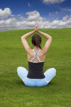 Athletic woman making yoga on a green meadow