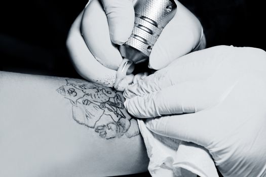 A tattoo artist applying his craft onto the hand of a female