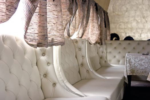 Row of white leather armchairs in bar interior