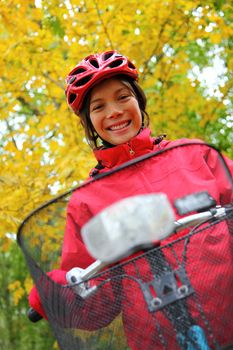 Woman biking in autumn forest. Strong colors.