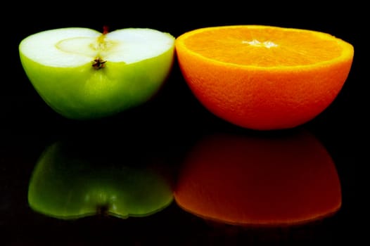 Apple and oranges isolated against a black background